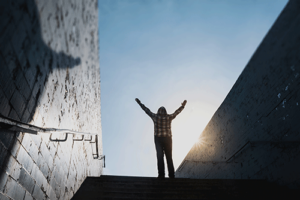 person at the top of stairs in an alumni refresher program raises their arms