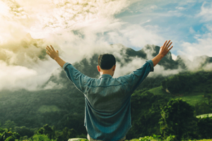 man raises arms outdoors in a wellness progam